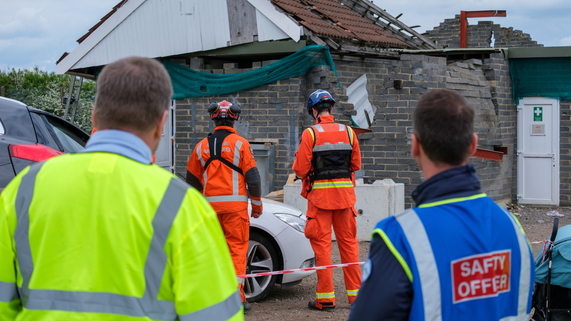 four people looking on at collapsed building