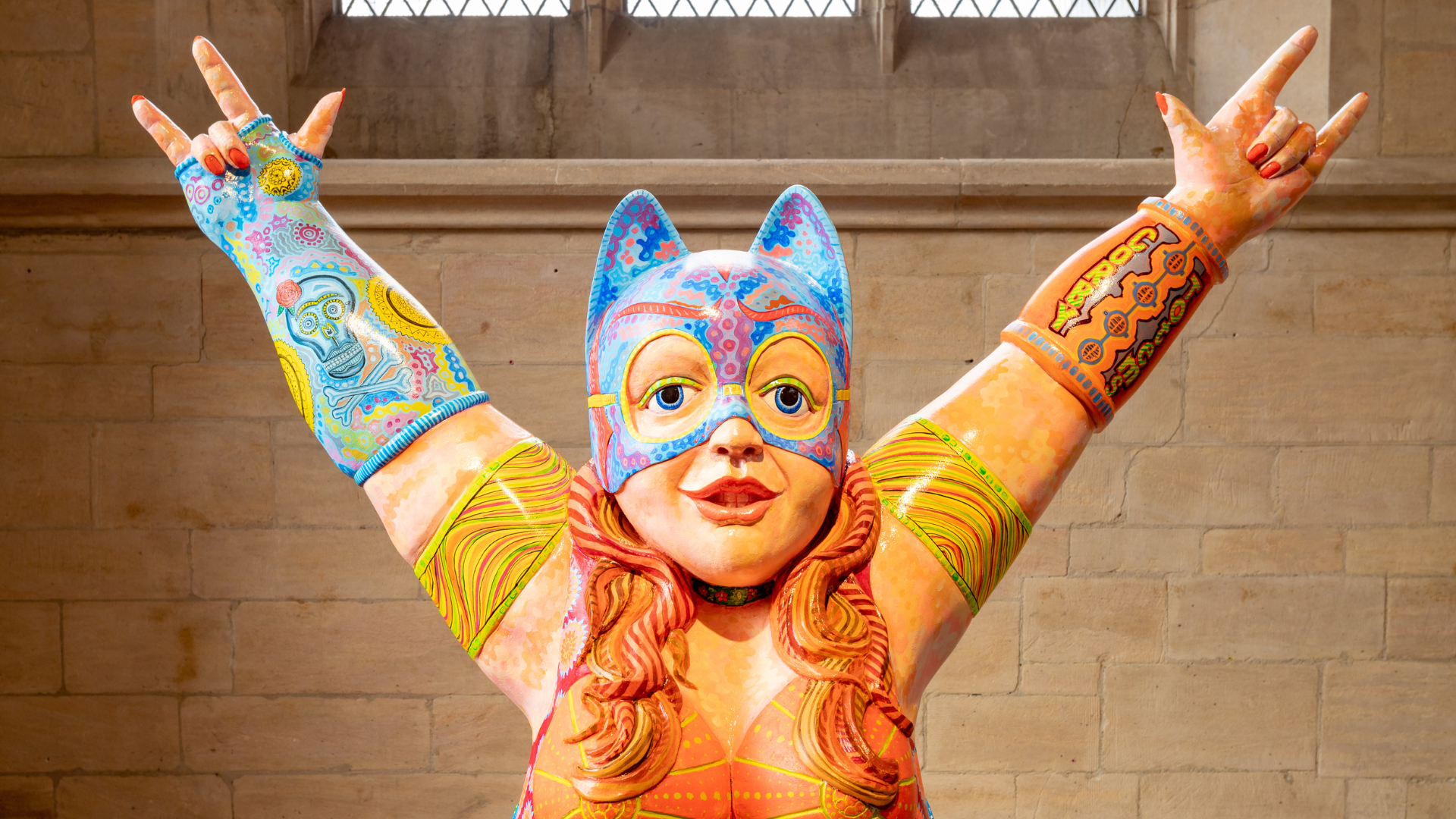 A psychedelic woman wearing a mask with ears putting her hands in the air, wearing decorative gloves, arm bands and top