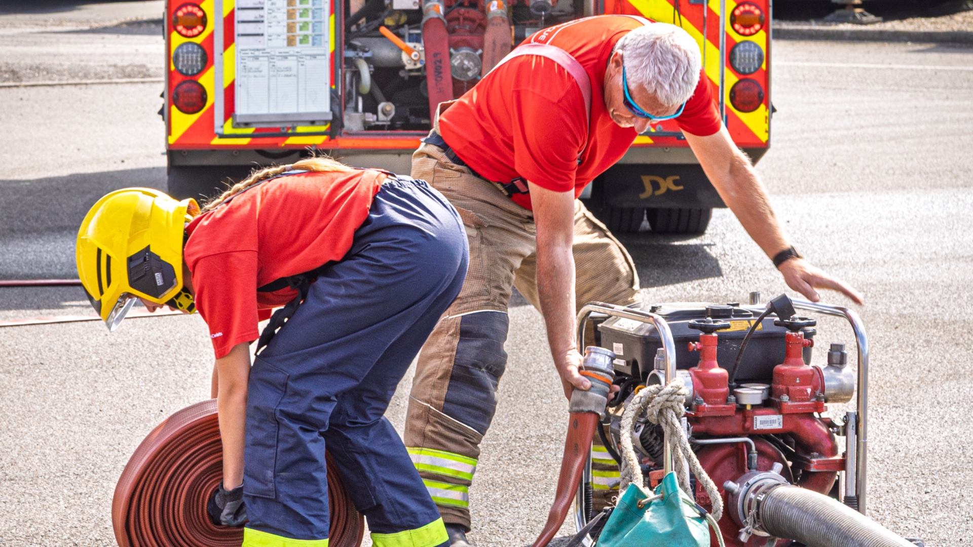 A cadet unreels a fire hose with the help of an instructor. Photo credit - Chris Bull