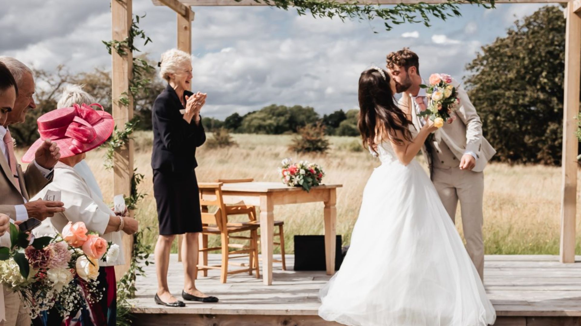 A bride and groom kissing in an outdoor wedding ceremony