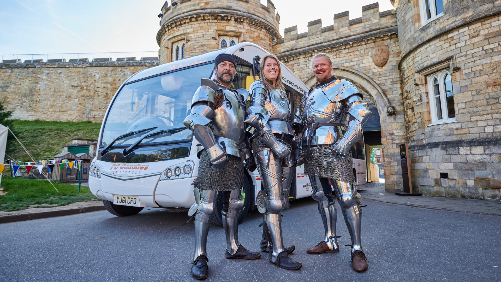 Three knights stand in front of a Lincolnshire bus at Lincoln castle