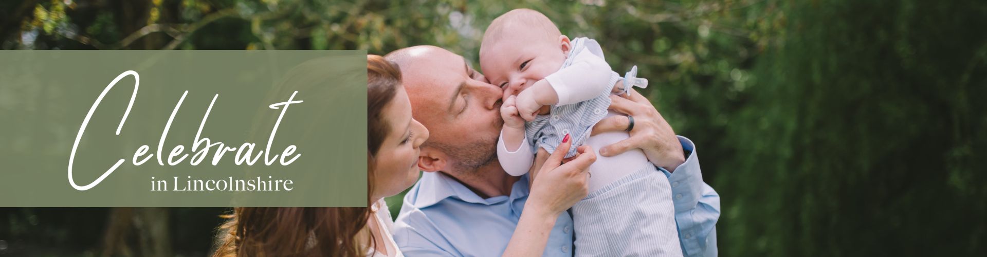 A couple holding up their baby and kissing it