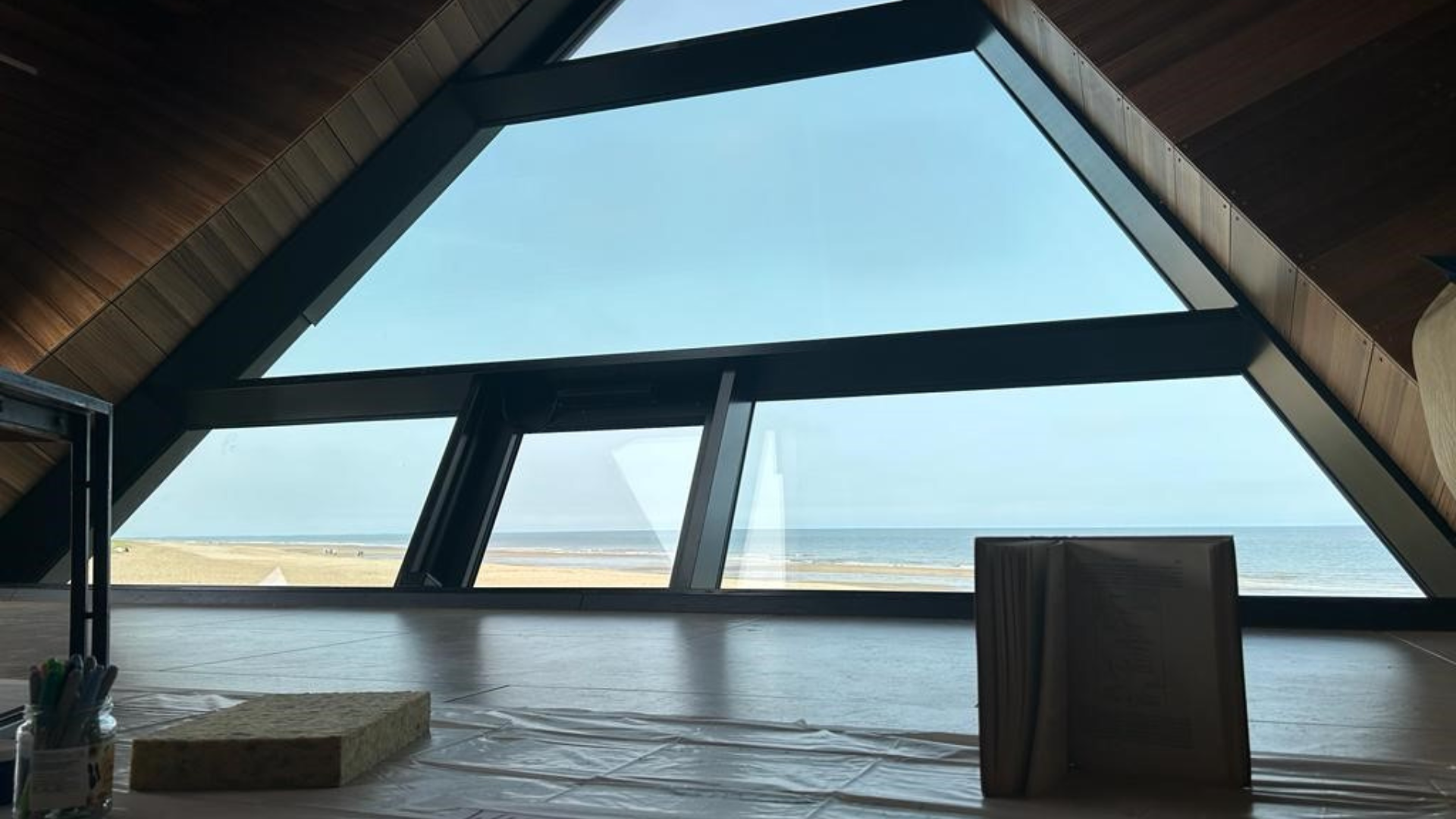 A large triangle window looking out to a beach