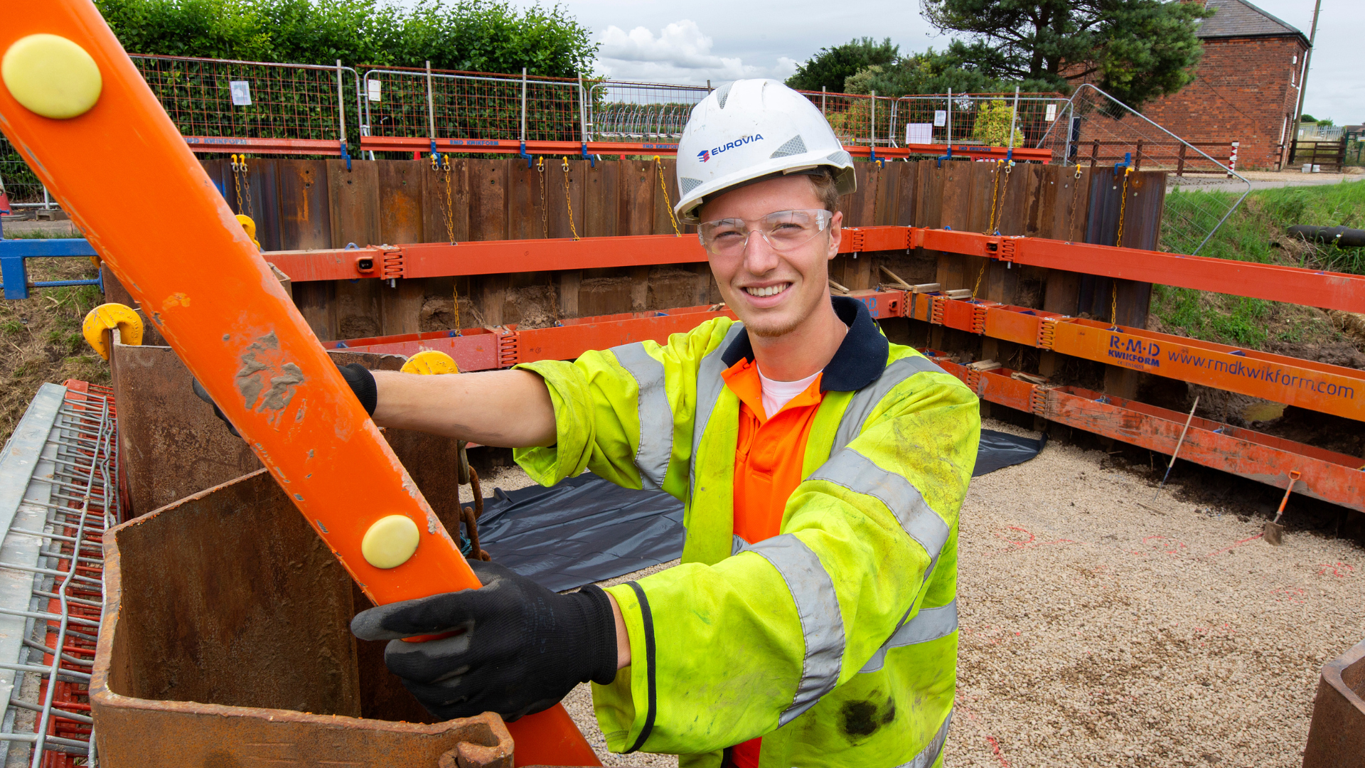 Charlie Butler, apprentice, stands in PPE on a ladder