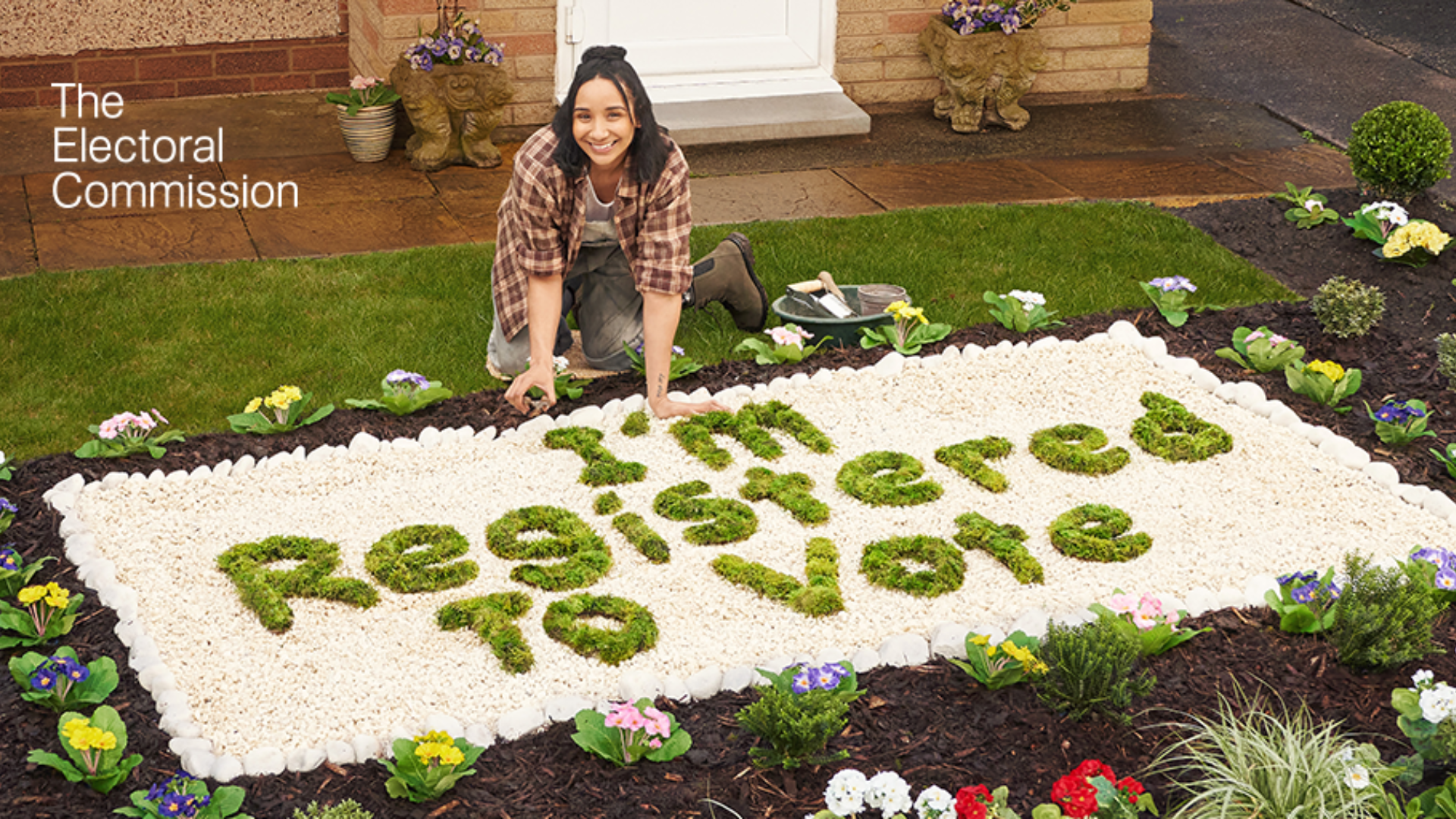 A lady gardening and written in the gravel with grass says I'm registered to vote
