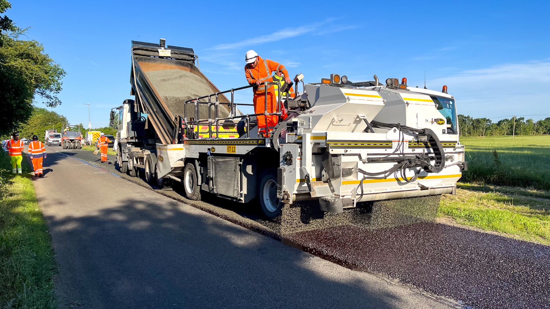 An image of a highways truck surface dressing a road