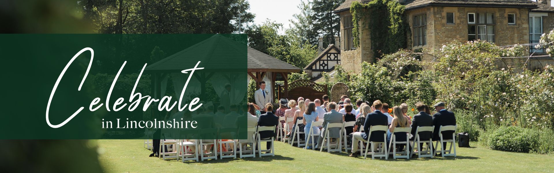 An outdoor ceremony with wedding party sat on chairs placed on the grass