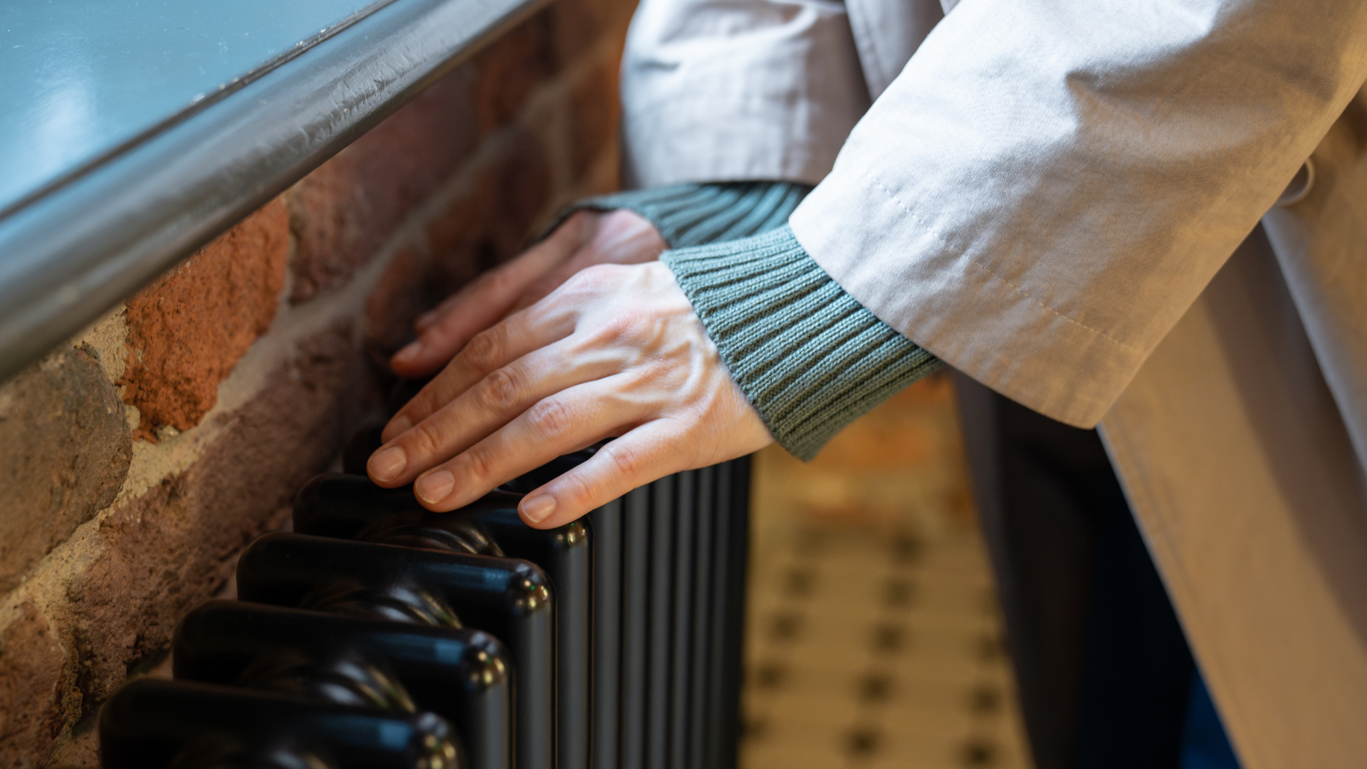 A lady warms her hands on a radiator