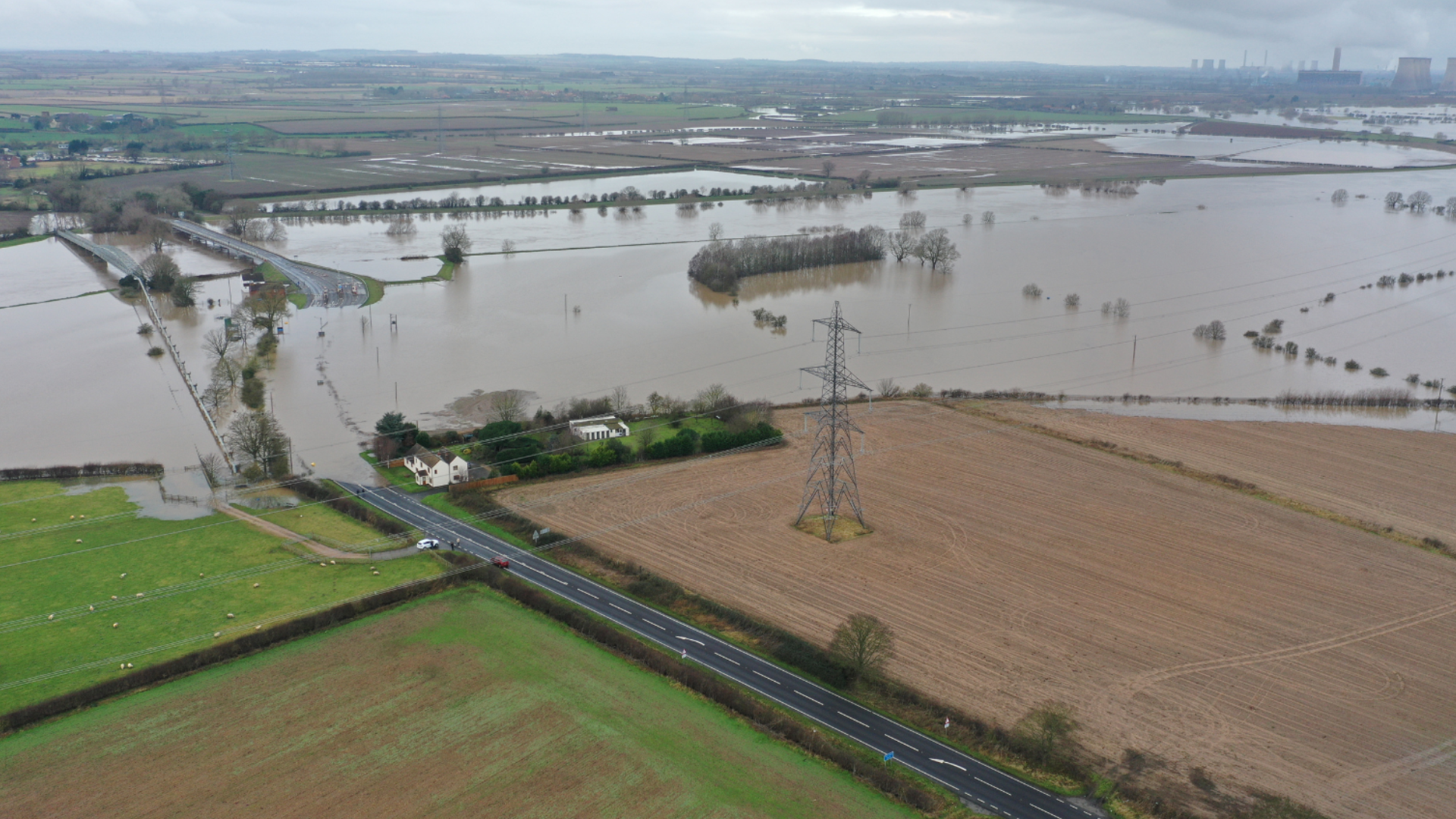 A flooded bridge with river water in the adjacent fields