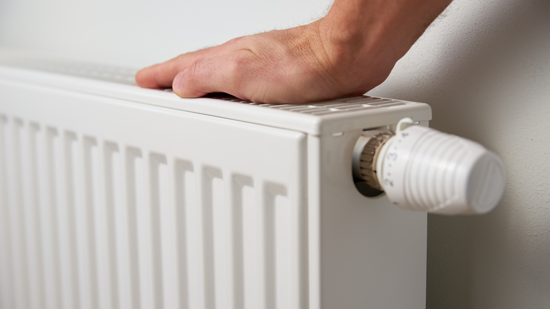 A hand touching the top of a radiator